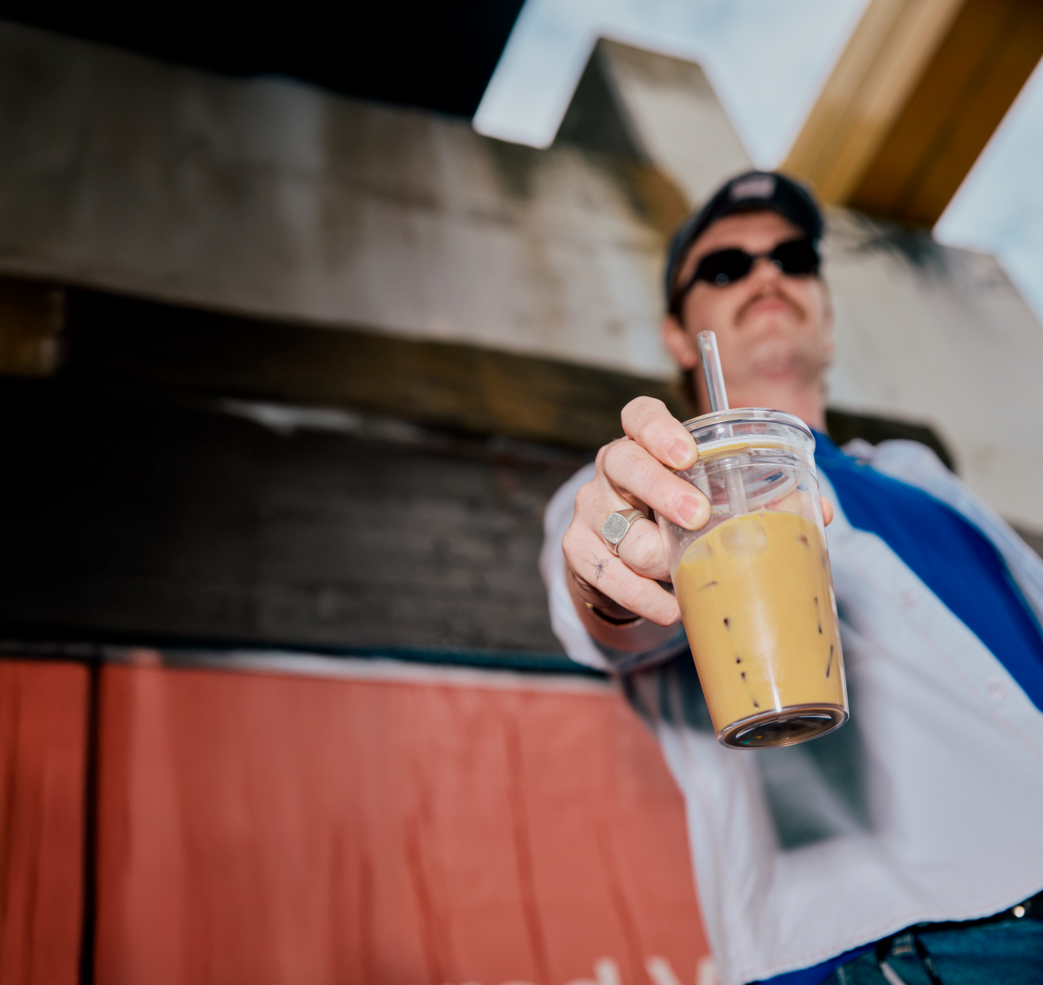 Person holding a glass of iced coffee outdoors