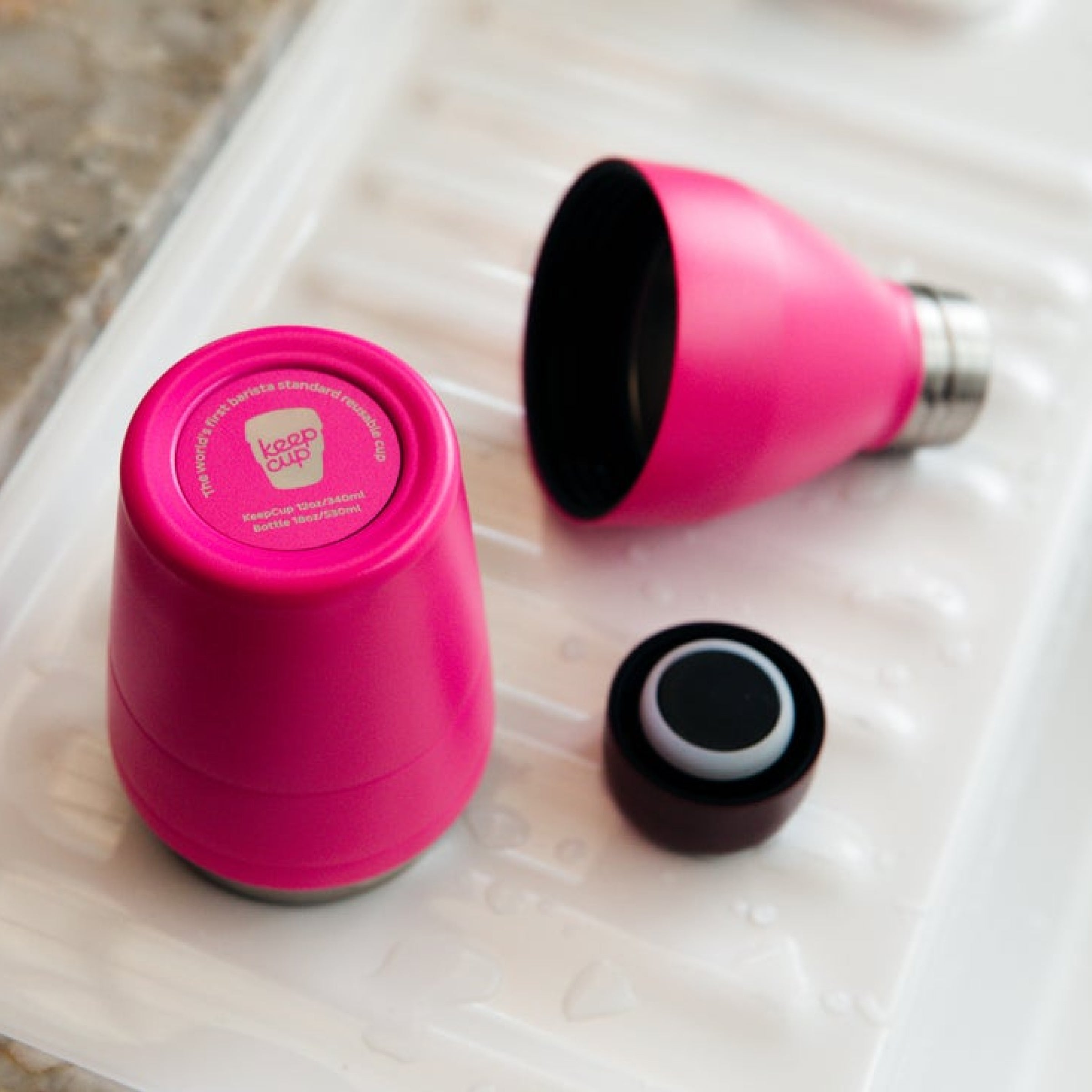 Pink KeepCup modular water bottle taken apart for cleaning on a white surface