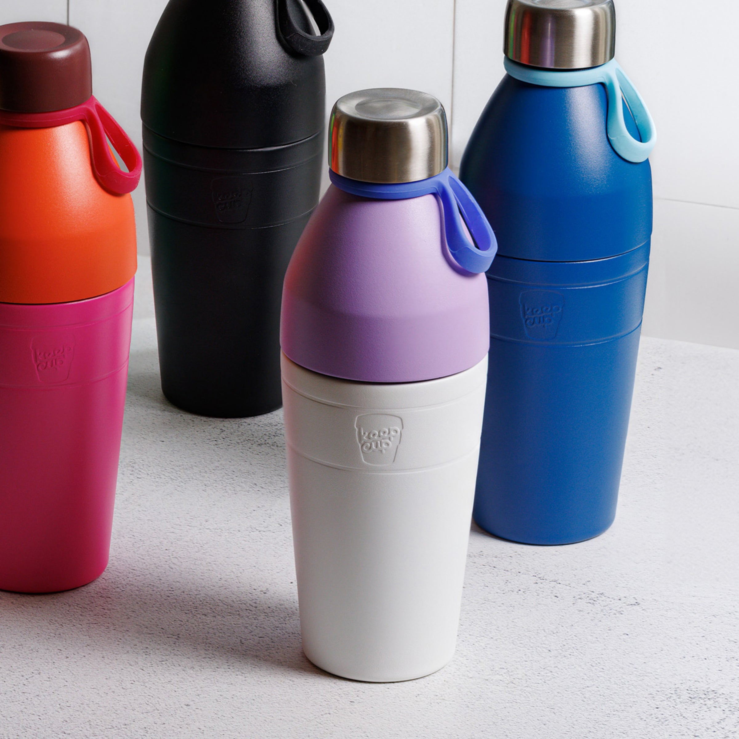 Four colourful KeepCup water bottles on a light surface.
