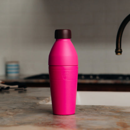 Pink KeepCup insulated water bottle on a kitchen counter with a blurred background