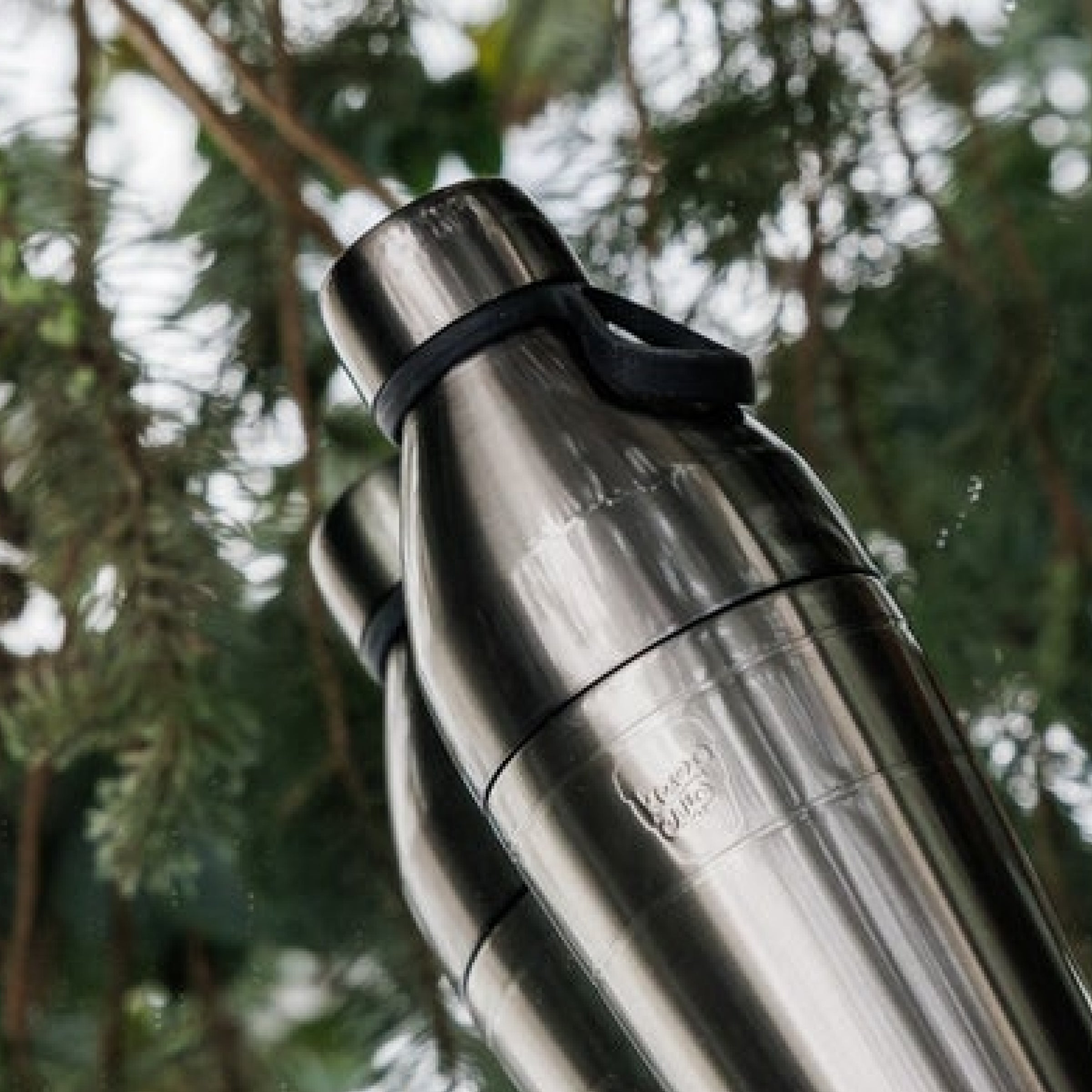 KeepCup Nitro water bottle with a black carry hang against a mirror surface in nature background