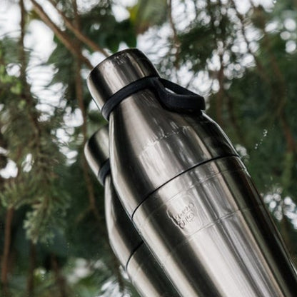 KeepCup Nitro water bottle with a black carry hang against a mirror surface in nature background