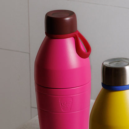 2 different KeepCup insulated bottles, one pink with maroon lid and the other yellow with silver lids on a light gray background