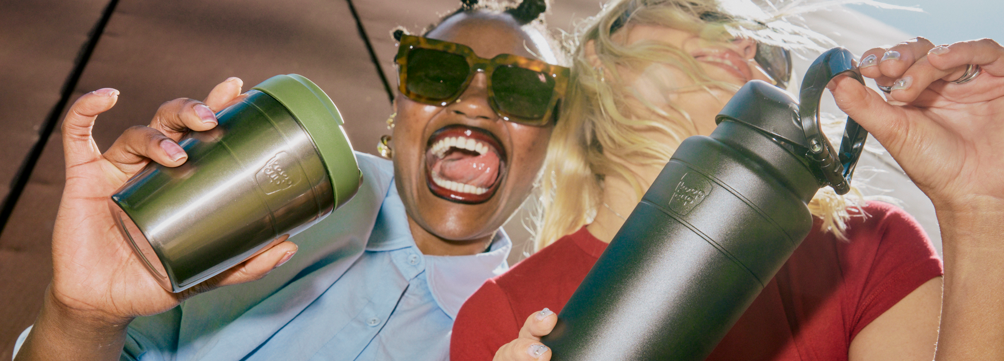 Two people holding an Ora insulated water bottle and a Commuter travel mug with a colorful background