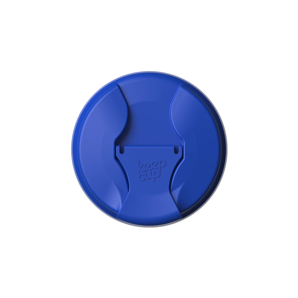 Top-down view of the Commuter Flip Lid in Electric Blue, showing the circular lid with its closed sipper opening and embossed KeepCup logo in the center.