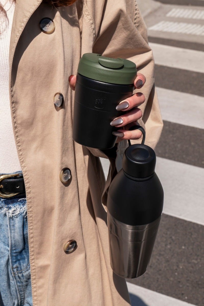 Woman on zebra crossing holding KeepCup Commuter and Helix Bottle in one hand
