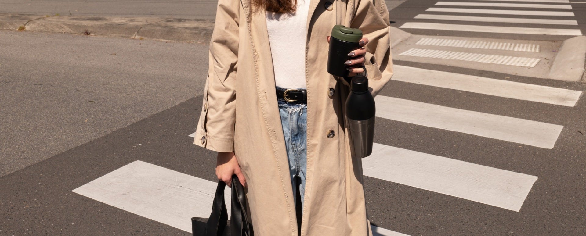 Woman on zebra crossing holding KeepCup Commuter and Helix Bottle in one hand