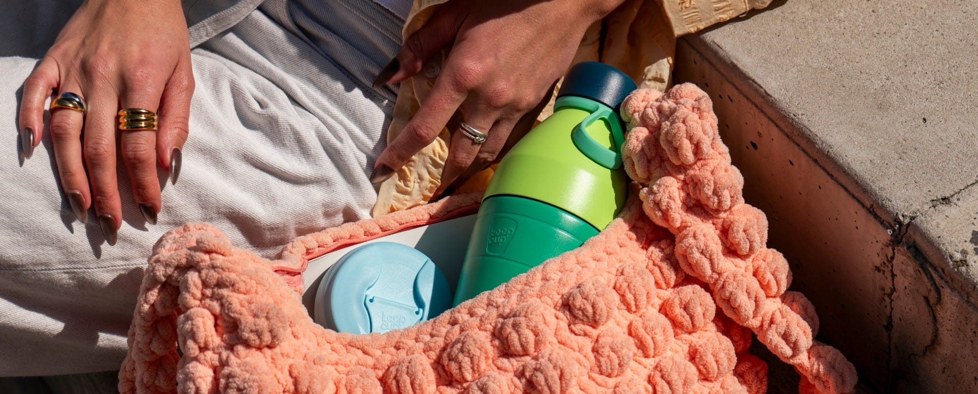 Woman leaning on step with KeepCup Helix Bottle and Commuter Lid Cloud sticking out of bag