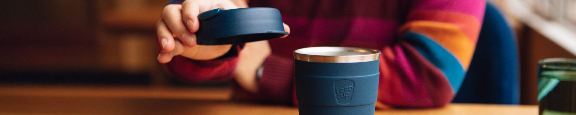 Woman sitting at table and lifting off the lid of Thermal cup in 12oz 
