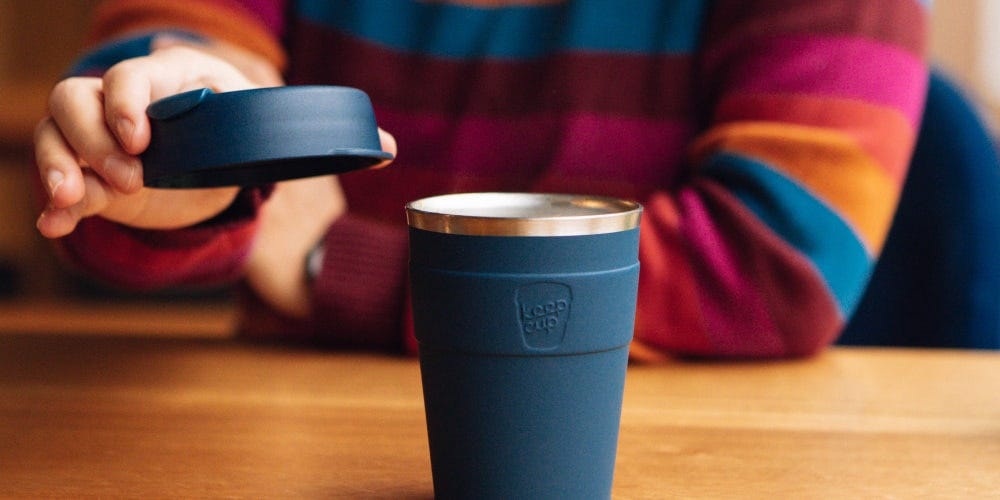 Woman sitting at table and lifting off the lid of Thermal cup in 12oz 
